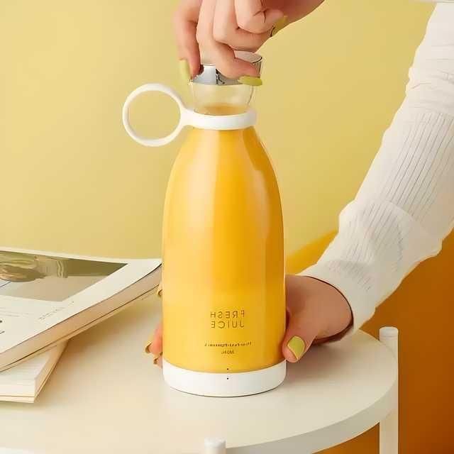 Yellow juice bottle with a white cap being held by a person against a yellow background